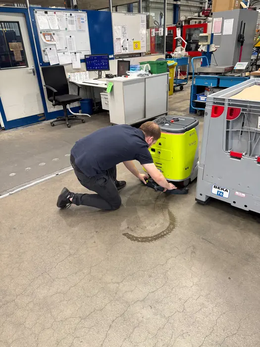 KOMJAN Techniker richtet einen Reinigungsroboter in einer Produktionshalle ein